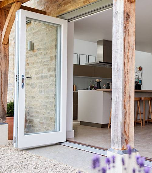 Senior Couple Standing And Looking Out Of Kitchen Door Drinking Coffee